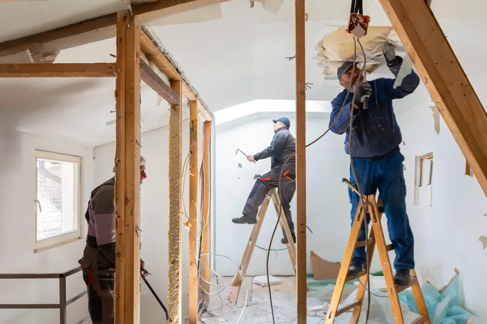 Artisan à genoux installant un parquet en chêne massif à chevrons dans un intérieur résidentiel