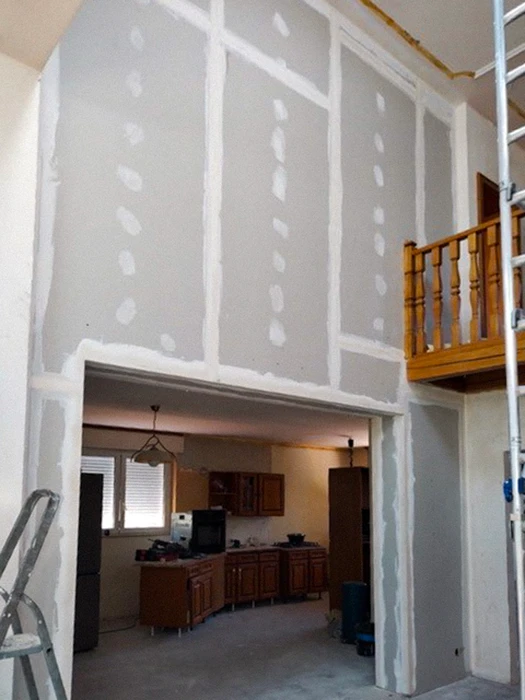 Chantier de rénovation intérieure en cours avec ouvriers équipés de casques de protection