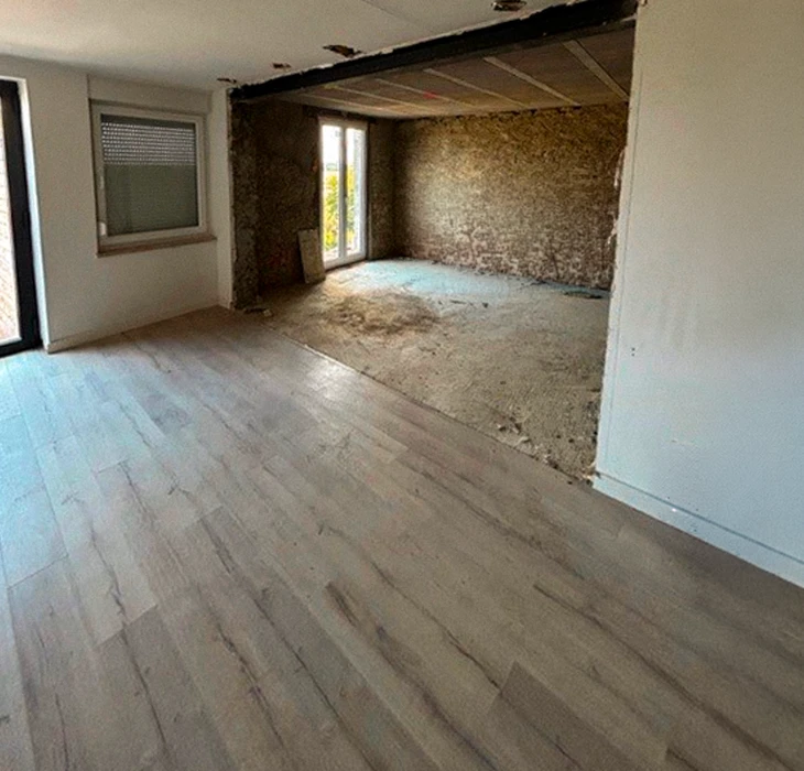 Plasterer utilisant une torche de finition pour lisser un nouveau plâtre à la surface d'un mur à l'intérieur d'une maison pendant les travaux de rénovation ou de construction