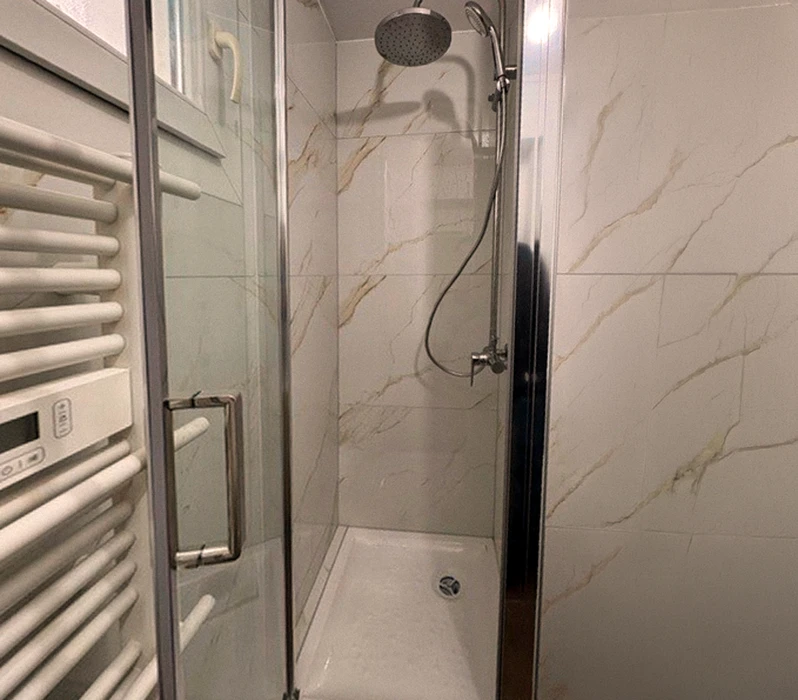 Chantier de rénovation intérieure avec murs en briques creuses apparentes, câbles électriques bleus en attente, escalier avec rampe en fer forgé décorative